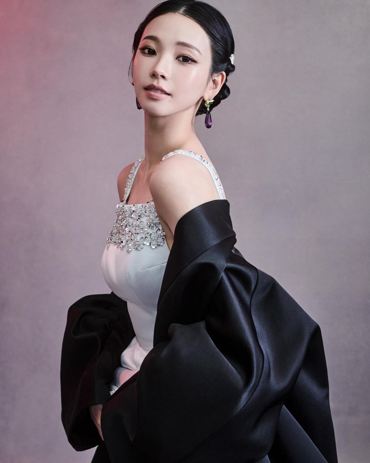 Karina in a white Prada gown and black cape